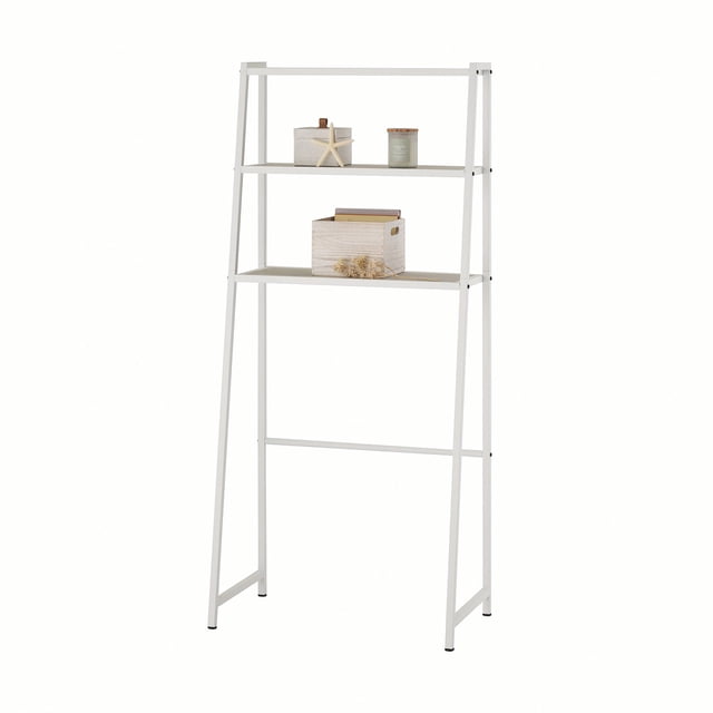trinity® 3-tier over-the-toilet shelving rack - assorted colors white three-tier over-the-toilet steel shelving rack with angled frame and three staggered rectangular shelves (shallow top, deeper middle and bottom), matte white finish, crossbar support and small staged jars and a wooden box on shelves. Often used for bathroom storage or linen organization.