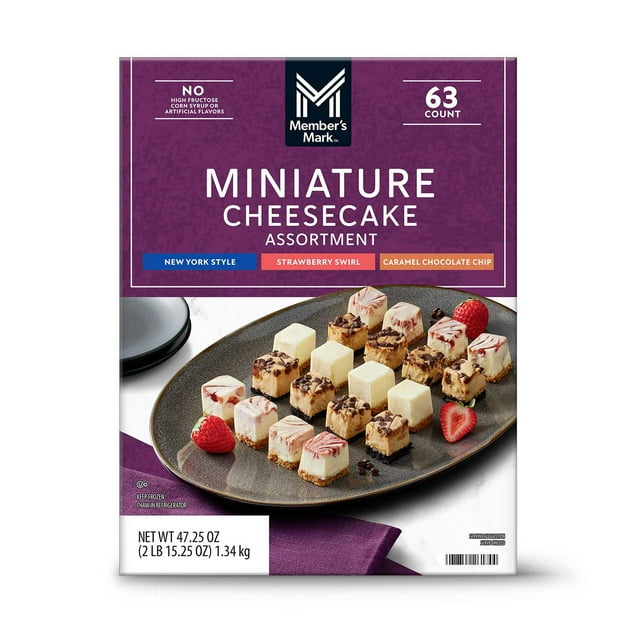 member's mark 1"x1" cheesecake minis, variety pack, 63 ct. Individually-wrapped mini cheesecakes on a front-facing box image with a dark serving platter holding three rows of New York Style, Strawberry Swirl and Caramel Chocolate Chip pieces; visible graham cracker and cookie crusts, strawberry swirls and chocolate-chip pieces, garnished with whole strawberries, ideal for parties, showers or catering trays.