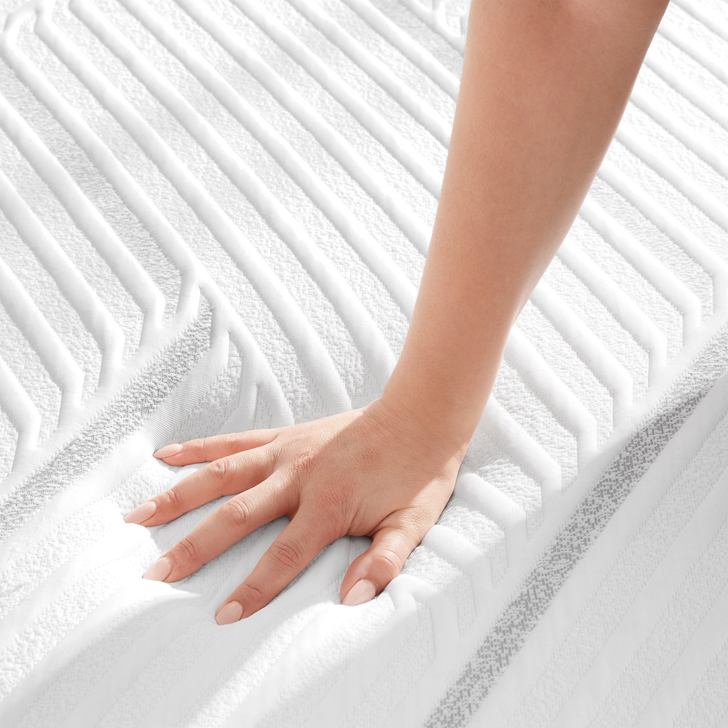 Close-up of hand pressing down on mattress surface showing firmness pattern