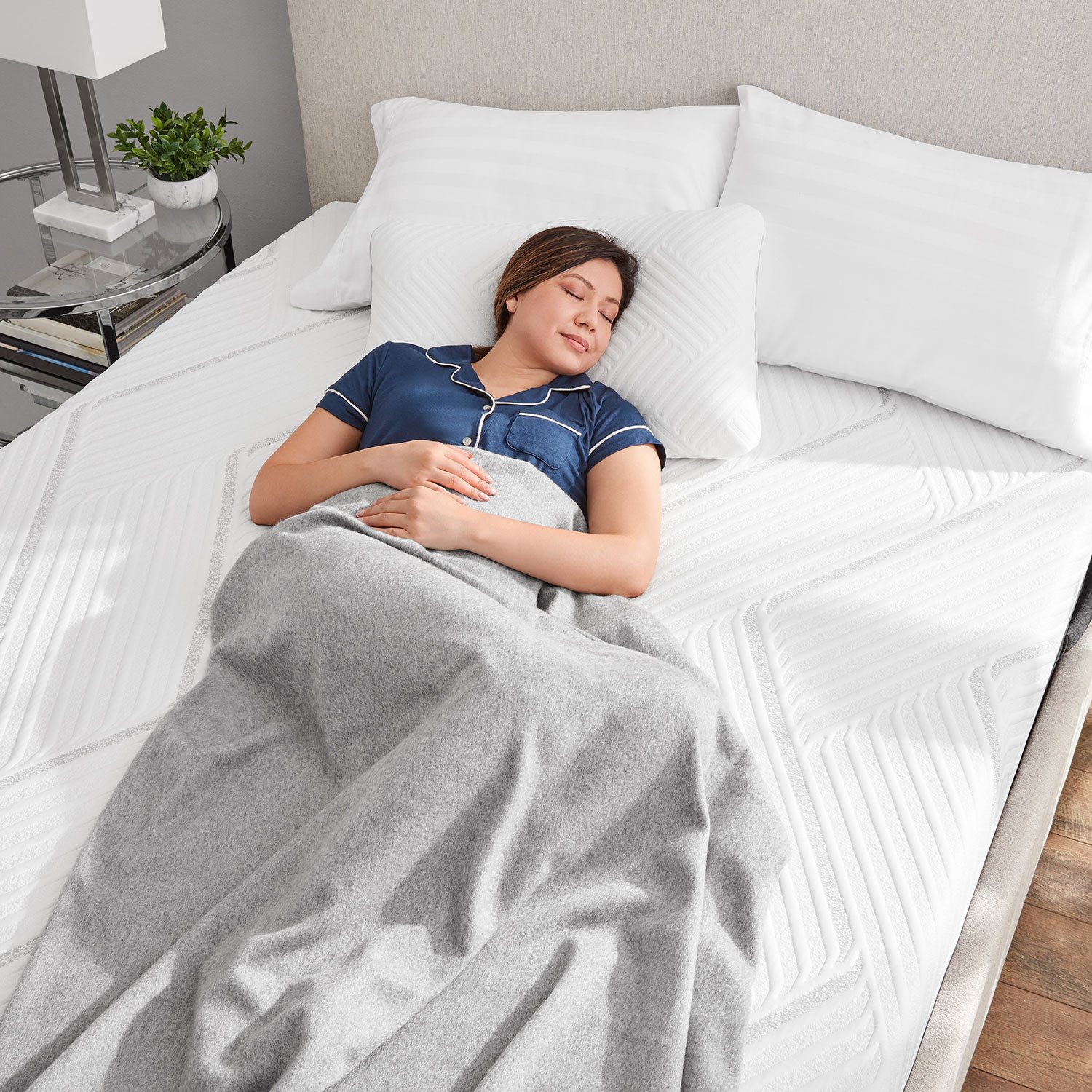 Person lying on back on a mattress with white bedding